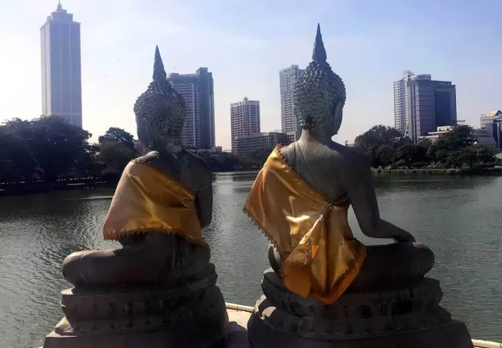 Dwie posągi Buddy z widokiem na nowoczesną panoramę stolicy Sri Lanki.