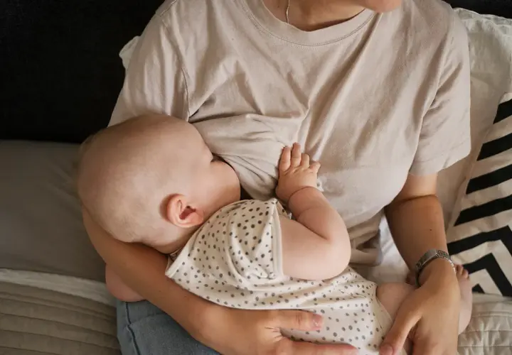 Un neonato si nutre al seno, un momento intimo che celebra il legame tra madre e figlio. Il ciclo della vita continua con l'allattamento.