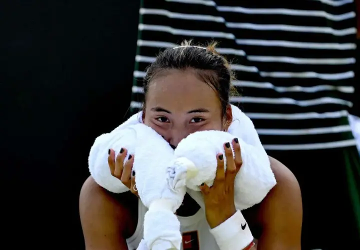 Zmęczona zawodniczka zheng tennis wyciera twarz ręcznikiem.