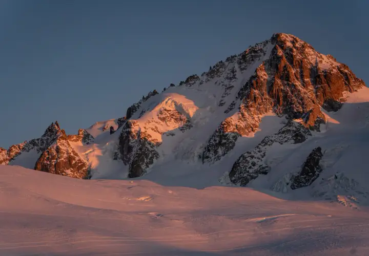 Ośnieżone szczyty Alp o wschodzie słońca, oświetlone złotym blaskiem. Widok na trasę Haute Route, gdzie lodowce i skaliste zbocza tworzą majestatyczny krajobraz.
