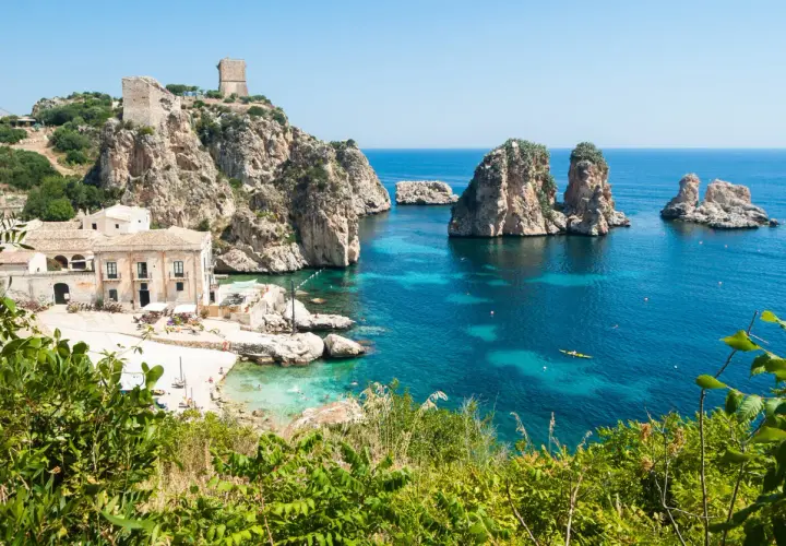 A picturesque bay with turquoise waters, rocky islets, and a historic tower, showcasing one of the most beautiful places in Sicily.