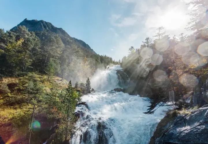 Cascada rugiente en un bosque de montaña, con rayos de sol atravesando la bruma. Un paisaje espectacular que evoca la fuerza de la naturaleza en el **pont de espagne**.