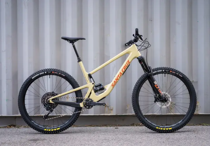 A tan 2020 Santa Cruz Hightower mountain bike with black wheels and orange "Santa Cruz" lettering.