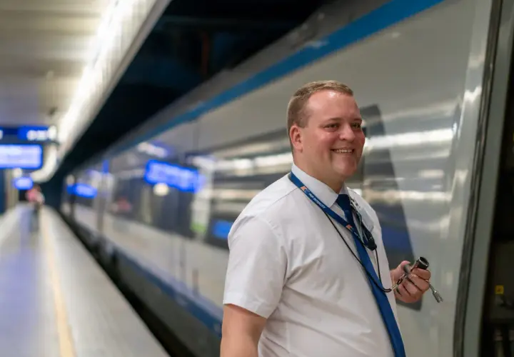 Uśmiechnięty mężczyzna w białej koszuli i granatowym krawacie, z identyfikatorem PKP Intercity, trzymający klucz. To jego pierwszy dzień po kursie na konduktora Intercity.