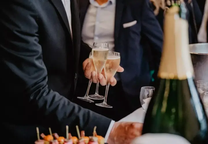 Des flûtes de champagne pétillant pour le vin d'honneur mariage. Des canapés colorés et une bouteille de champagne en avant-plan.