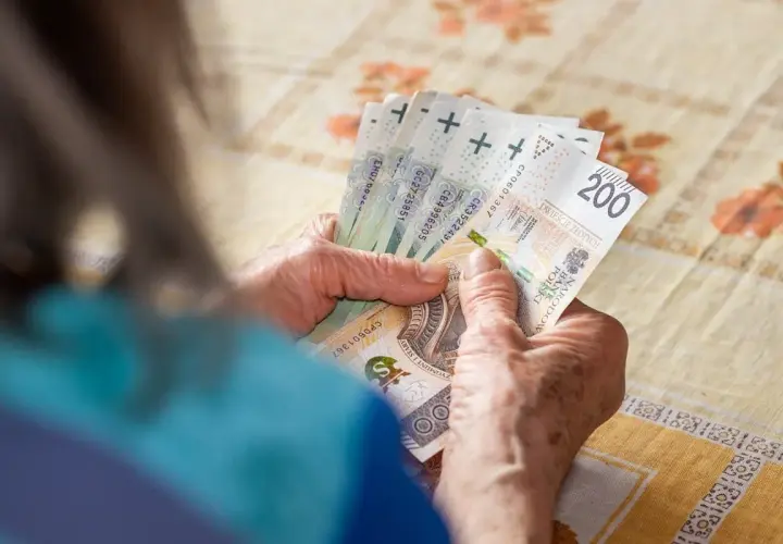 Dłonie starszej osoby liczą polskie banknoty 200 zł i inne nominały.