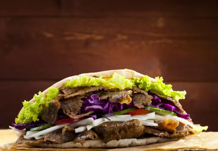 Kebab z mięsem, sałatą, czerwoną kapustą i warzywami w picie.