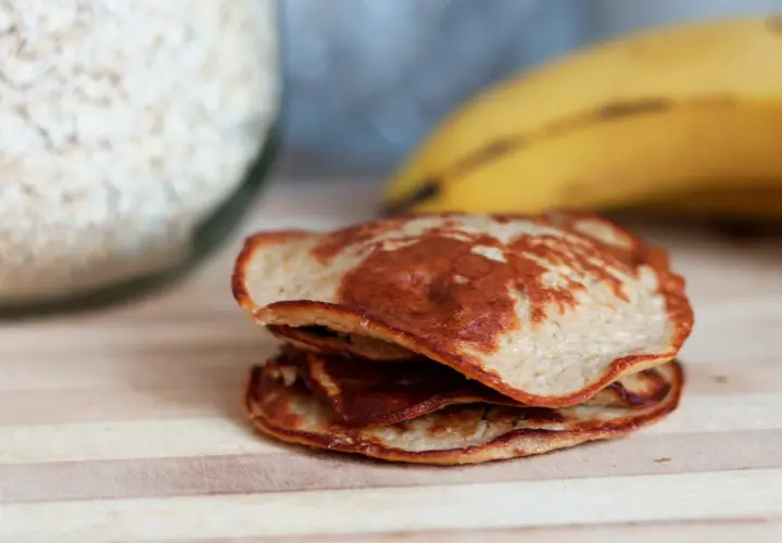 En hög med gyllenbruna bananpannkakor, redo att avnjutas. Ett enkelt bananpannkaka recept för en god frukost.