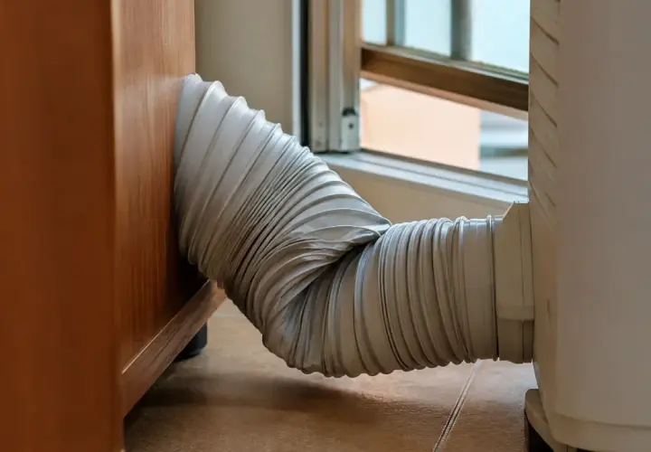El tubo de un aire acondicionado portátil, conectado a una ventana, parece un poco torcido. ¡Espero que mi pinguino no enfria!