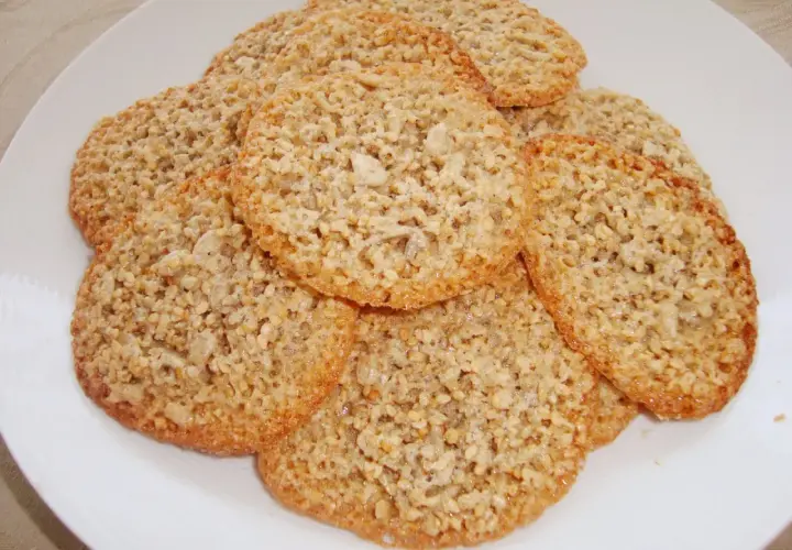 En hög med krispiga, gyllene glutenfria havreflarn på en vit tallrik. Perfekta för fikat!