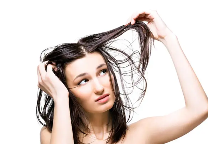 Mujer con cabello mojado, pensativa sobre lavarse el pelo todos los días.