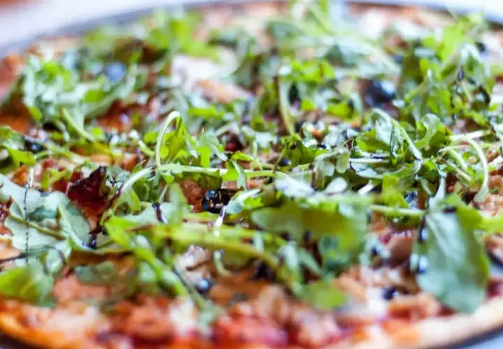 Pyszna pizza z tuńczykiem, rukolą i oliwkami, polana sosem balsamicznym. Idealna na szybki obiad.