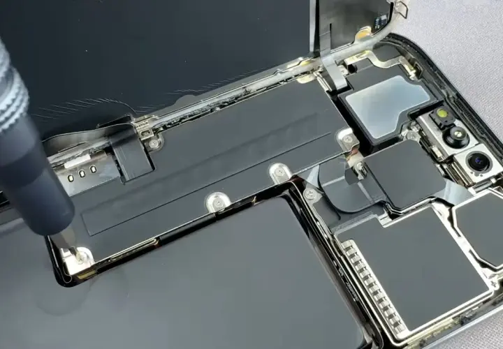 Naprawa telefonu z powodu słabej baterii w telefonie. Wkrętak odkręca śrubkę przy baterii.