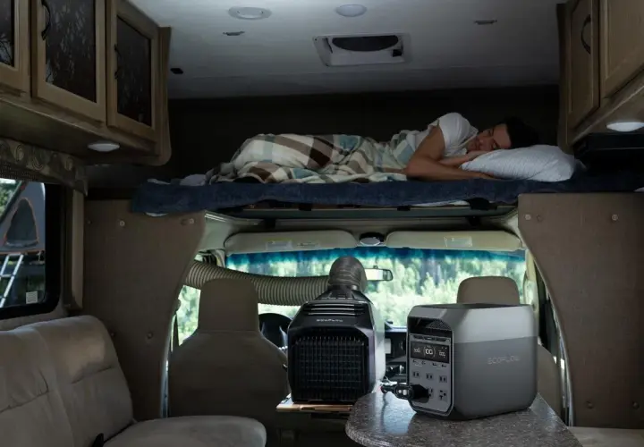 Un homme dort dans un camping-car 4 places. Une unité de climatisation portable et une station d'énergie sont visibles.
