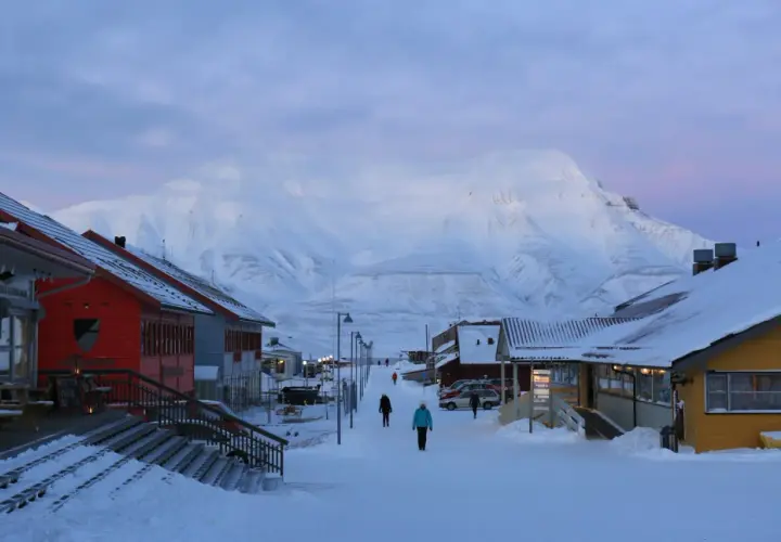 Śnieżna ulica w Longyearbyen, najwyżej położonym mieście na świecie, z górami w tle.