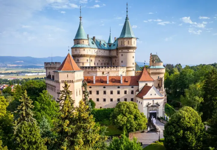 Majestatyczny zamek Bojnice, jeden z najpiękniejszych zamków na Słowacji, otoczony zielenią.