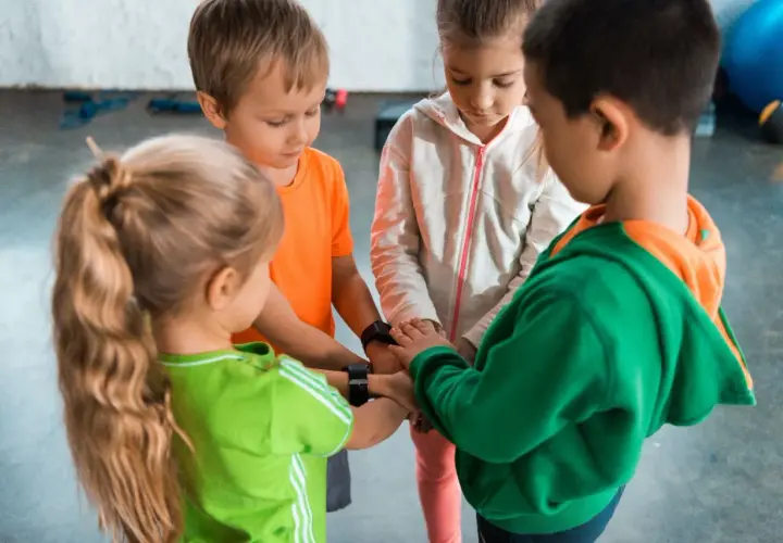 Dzieci w wieku 6-7 lat, tworząc krąg, łączą ręce. Może to być początek wspólnej zabawy lub rozwiązywania zagadek.