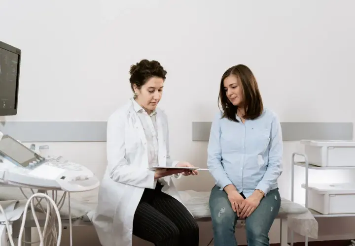 Medico spiega a paziente i risultati di un esame, forse un ecografia, discutendo del cerchiaggio cervicale.