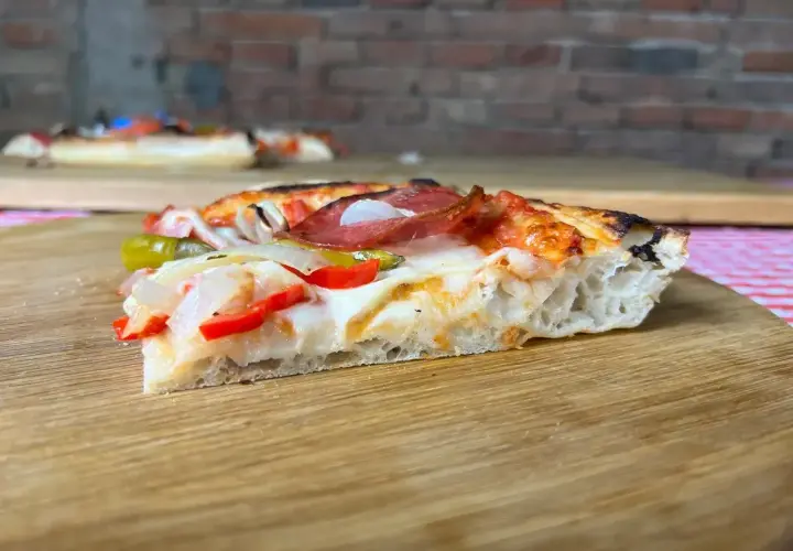 Ein Stück Pizza mit original italienischem Pizzateig Rezept Blech, belegt mit Salami, Paprika und Zwiebeln.