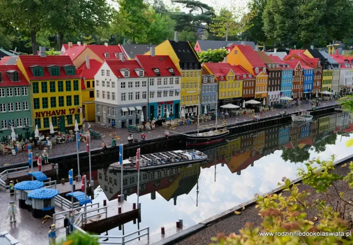 Kolorowe kamienice nad kanałem w miniaturowym Legolandzie Kopenhaga, z odbiciem w wodzie.
