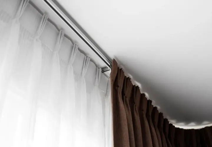 Elegancki karnisz mocowany do sufitu, z białymi i brązowymi zasłonami, tworzy przytulną atmosferę.
