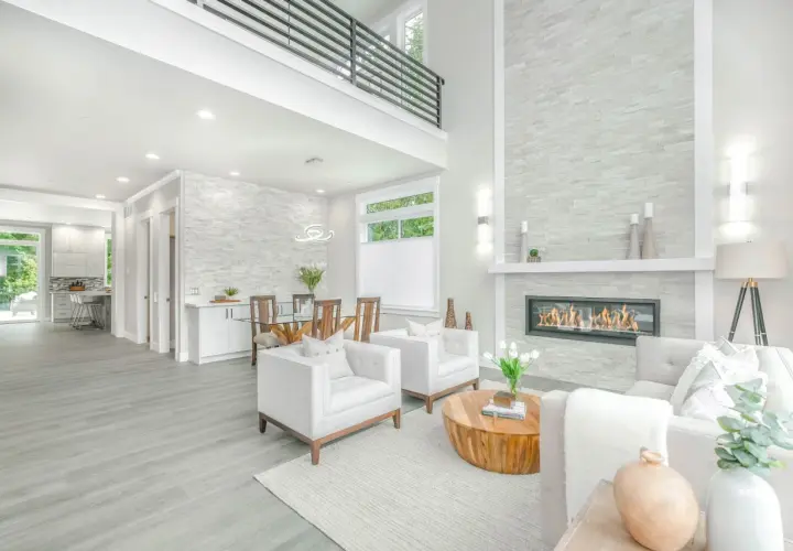 A modern living room with a fireplace, dining area, and kitchen, showcasing a full service interior design.