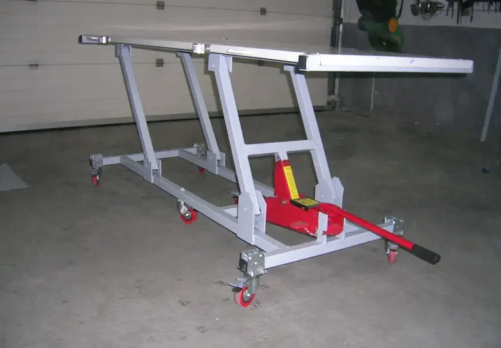 Elevador moto casero con gato hidráulico rojo, estructura metálica gris y ruedas. Ideal para reparaciones.
