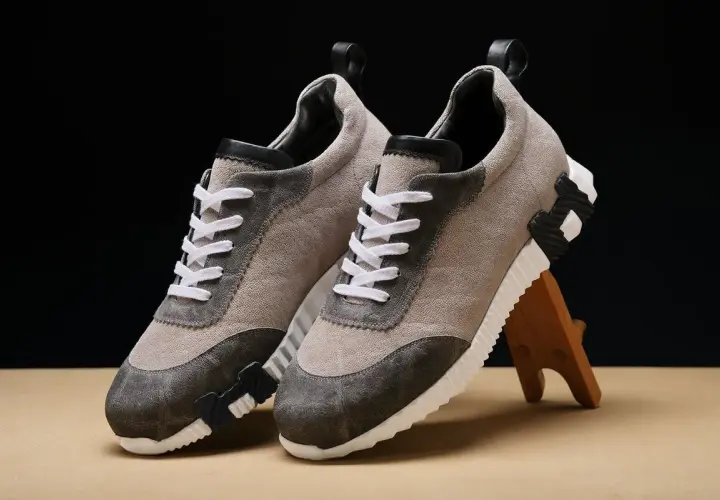 Ein Paar beigefarbene Sneaker mit grauen Akzenten und weißen Schnürsenkeln. Sie zeigen, wie orthopädische Schuhe aussehen können: stilvoll und bequem.