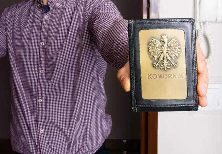 Mężczyzna w koszuli prezentuje legitymację komorniczą. To znak, że może nastąpić zajęcie egzekucyjne.