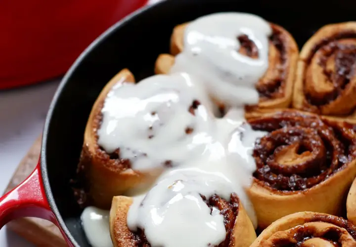 Deliciosos rollitos de canela recién horneados, cubiertos con un glaseado cremoso, listos para disfrutar.