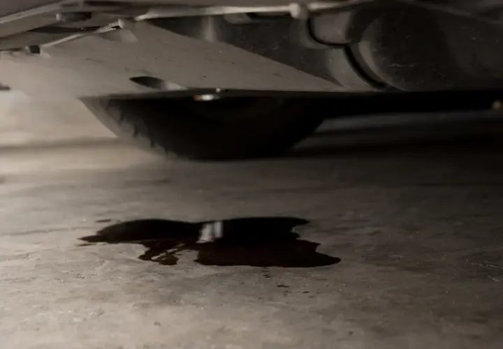 Mancha de aceite en el suelo bajo un coche. ¿Cuánto costará arreglar mi coche si pierde aceite?