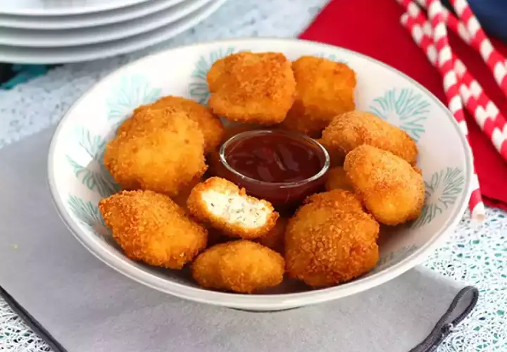 En skål med gyllene chicken nuggets och en liten skål med ketchup. Perfekt för en snabb och god måltid.