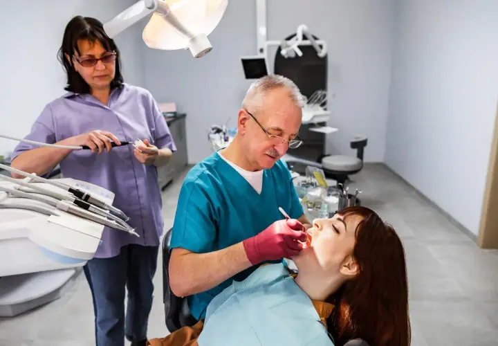 Dentista esamina una paziente. L'alitosi quando preoccuparsi? Chiedi al tuo dentista.