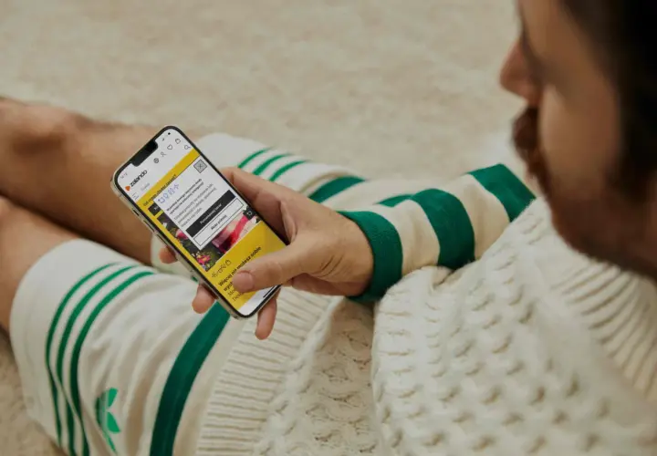 Mężczyzna przegląda telefon z aplikacją Zalando. Widoczna promocja: zalando - 15% na wszystko.