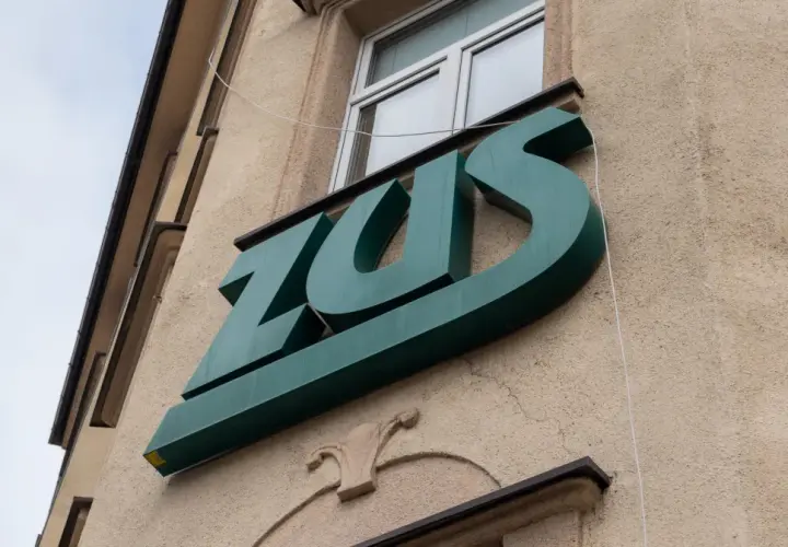 Zielone logo ZUS na budynku. Warto wiedzieć, jak wynagrodzenie chorobowe a składki ZUS wpływają na Twoje finanse.