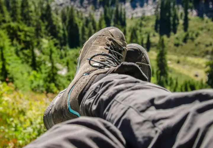 A hiker rests, their well-worn boots laced snugly. This image shows how hiking boots fit, offering comfort and support on the trail.