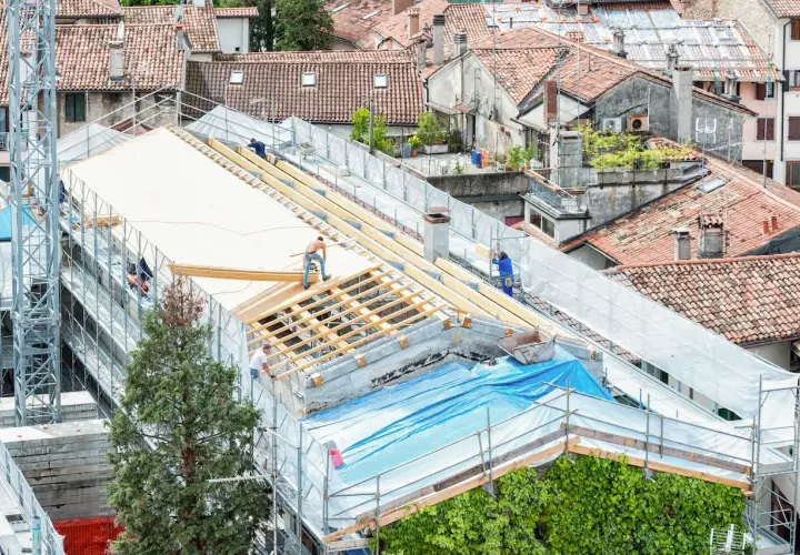 Pracownicy realizują projektowanie dachu, montując drewnianą konstrukcję na budynku.