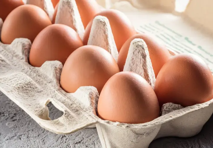 Des œufs bruns dans une boîte en carton. On hésite à manger un œuf après la date, par prudence.