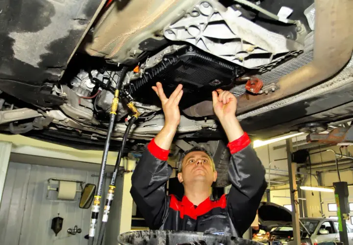 Mechanik wykonuje statyczną wymianę oleju w automatycznej skrzyni biegów, podłączając węże do układu.
