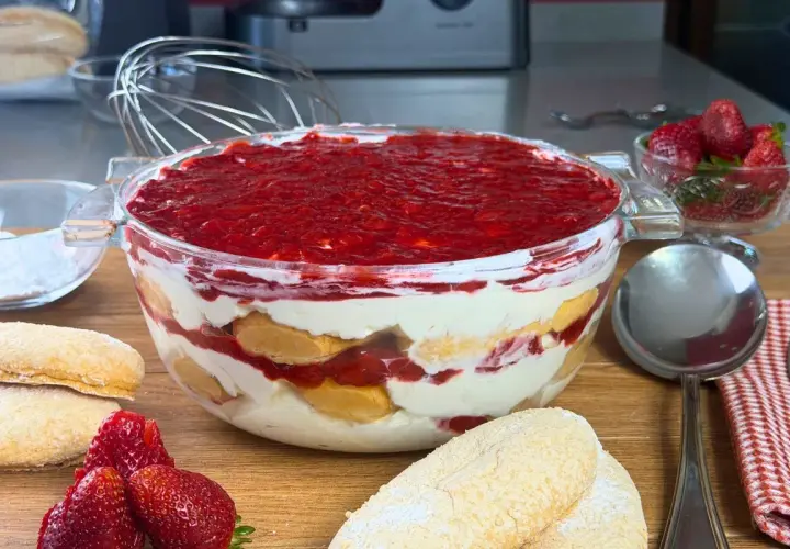 Un invitante tiramisù alle fragole in una ciotola di vetro, con savoiardi, crema e fragole fresche.