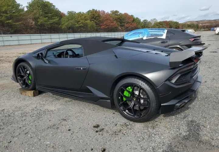 Matowy czarny lambo huracan z jaskrawozielonymi zaciskami hamulcowymi stoi na żwirowym placu.