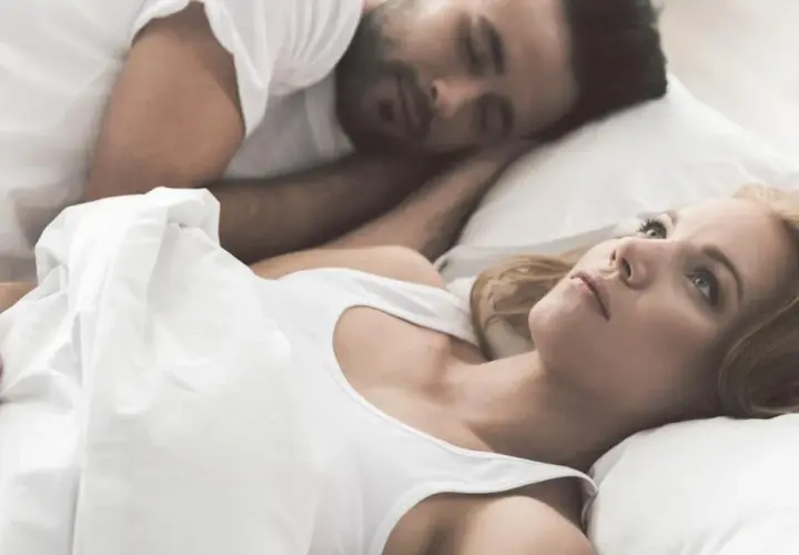 Kobieta leży obok śpiącego partnera, czując się jak sparaliżowana sennie.