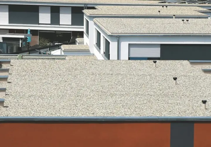 Mehrere moderne Gebäude mit verschiedenen **Flachdach Arten**, bedeckt mit Kies und mit sichtbaren Entlüftungsrohren.