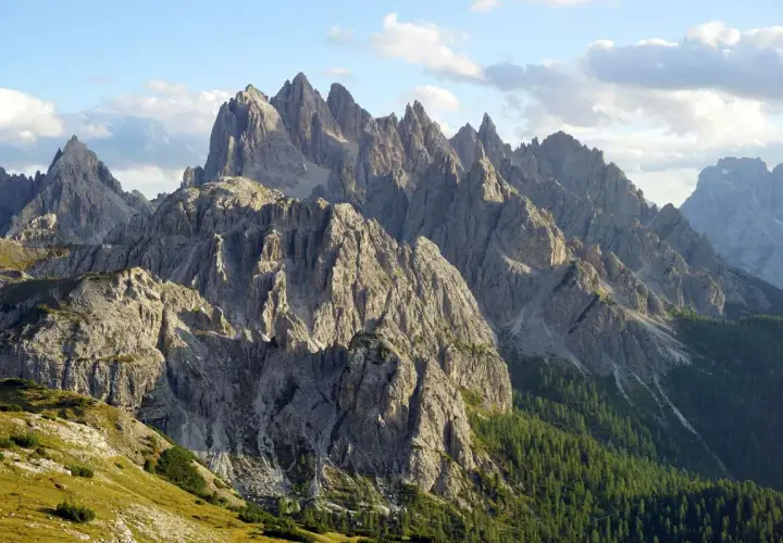 Majestatyczne szczyty Cadini di Misurina w Dolomitach, ostre jak zęby, wznoszą się ku błękitnemu niebu z chmurami.