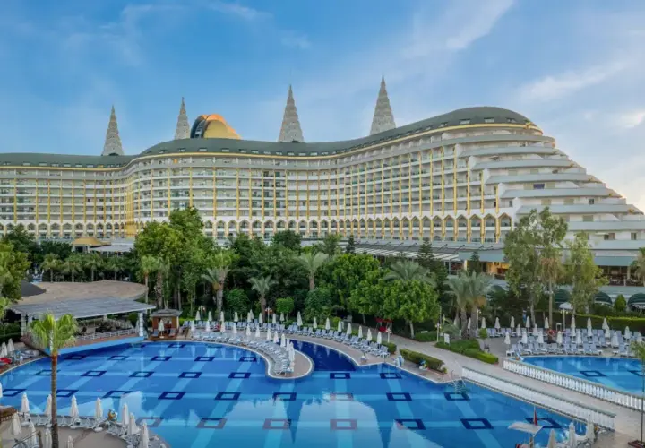 Luksusowy hotel Delphin Imperial Lara z basenem i leżakami, otoczony zielenią.