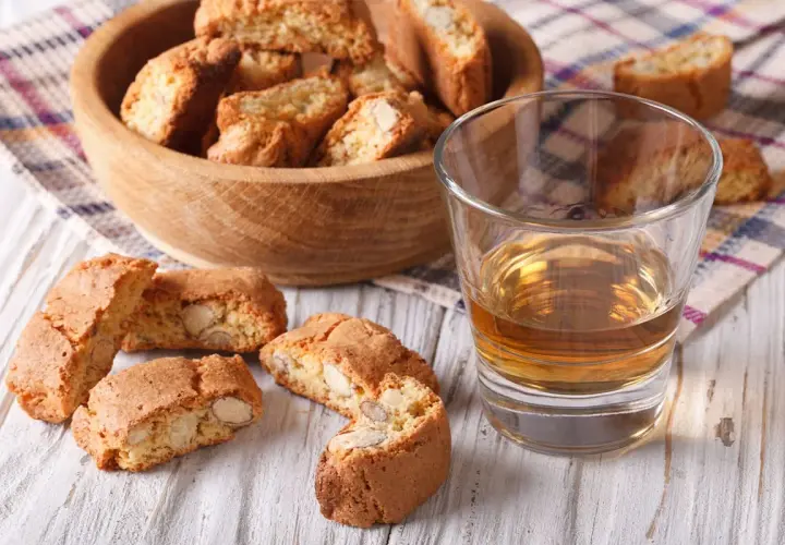 Kieliszek wina Vin Santo i cantucci z migdałami na drewnianym stole.