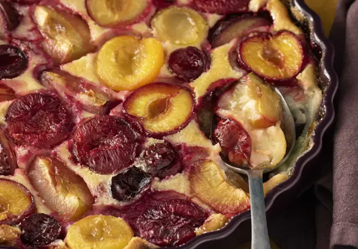 Un délicieux clafoutis aux prunes, aux couleurs vives et à la texture moelleuse, prêt à être dégusté.