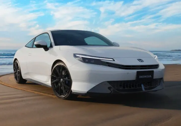 El Honda Prelude 2026 blanco, con su diseño deportivo, se luce en la playa bajo un cielo azul.