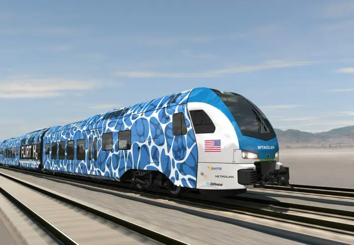 Nowoczesny pociąg Stadler FLIRT H2 z niebiesko-białym wzorem pędzi po torach.