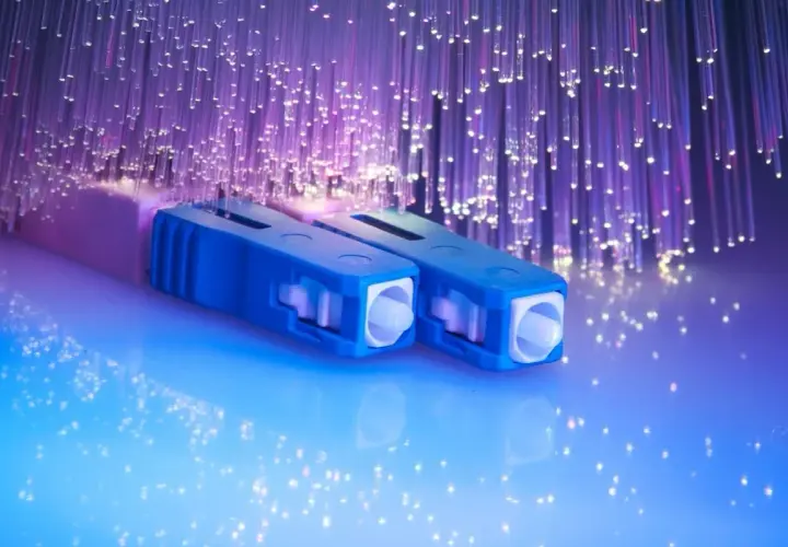 Connecteurs bleus pour télécommunication fibre optique, entourés de fils lumineux violets.